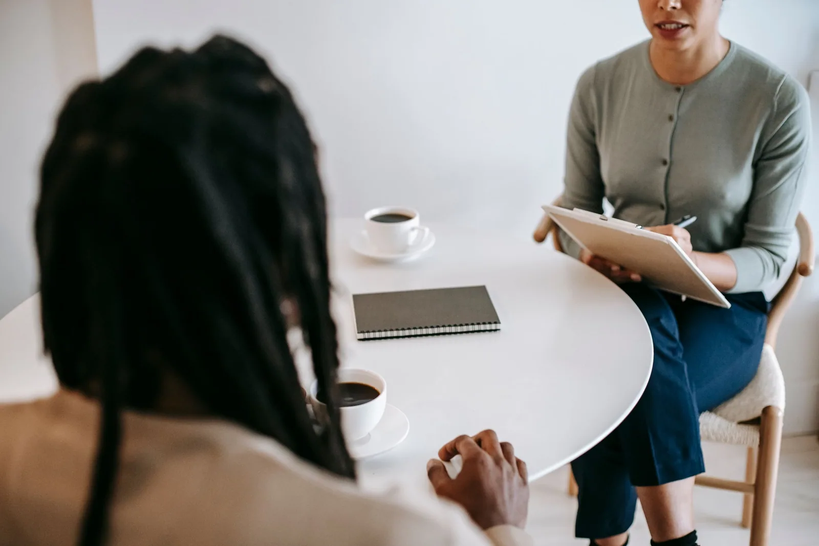 Dos personas conversan junto a una mesa con un cuaderno